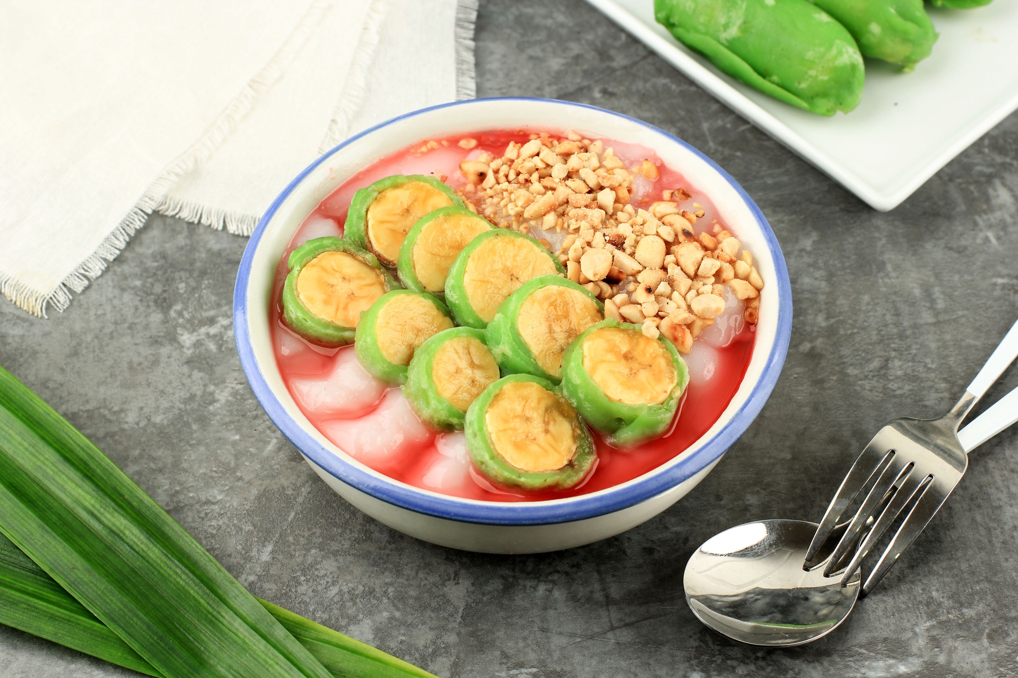 kuliner makassar Es Pisang Ijo Ripe Banana Rolled with Green Thin Crepes Served with Rice Porridge